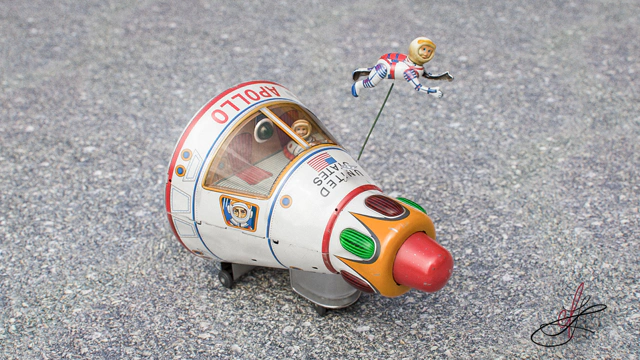 White vintage Apollo starship tin toy standing on an asphalt road.