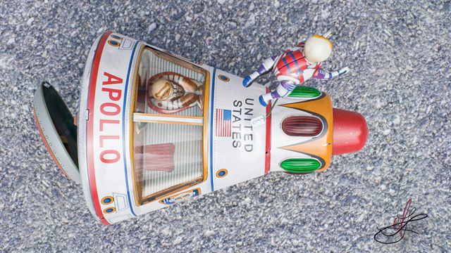 Bird's eye shot of a vintage Apollo starship tin toy standing on an asphalt road.