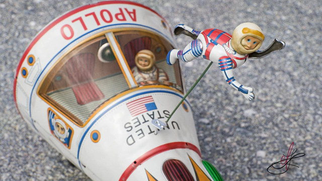 Long shot of spacewalking astronaut floating on a wire above the Apollo starship tin toy.