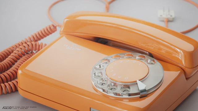 Close up on the rotary dial of the telephone. The dial comprises of three parts: the orange center which has embossed white numbers from zero to nine, the actual plexiglass transparent dial with finger holes, the white but slightly yellowed plastic base with imprinted large black digits, and finally the metallic element in the shape resembling an arror, which blocks the finger from rotating the dial past a certain angle.